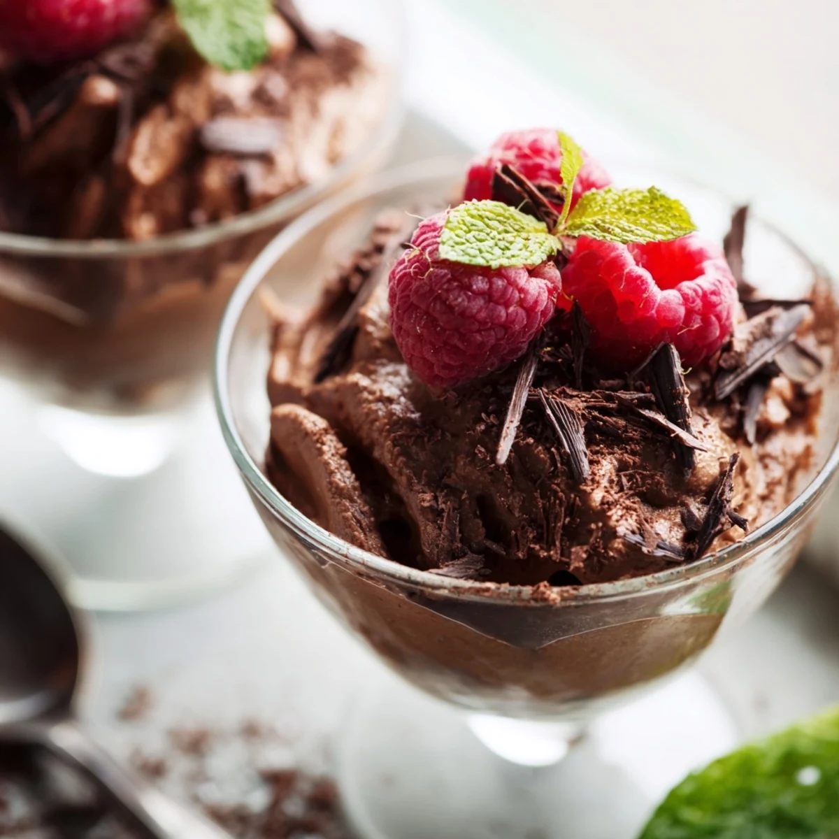 Chocolate Mousse Cups with Raspberries topped with fresh berries and mint, a creamy chilled dessert ready to serve.