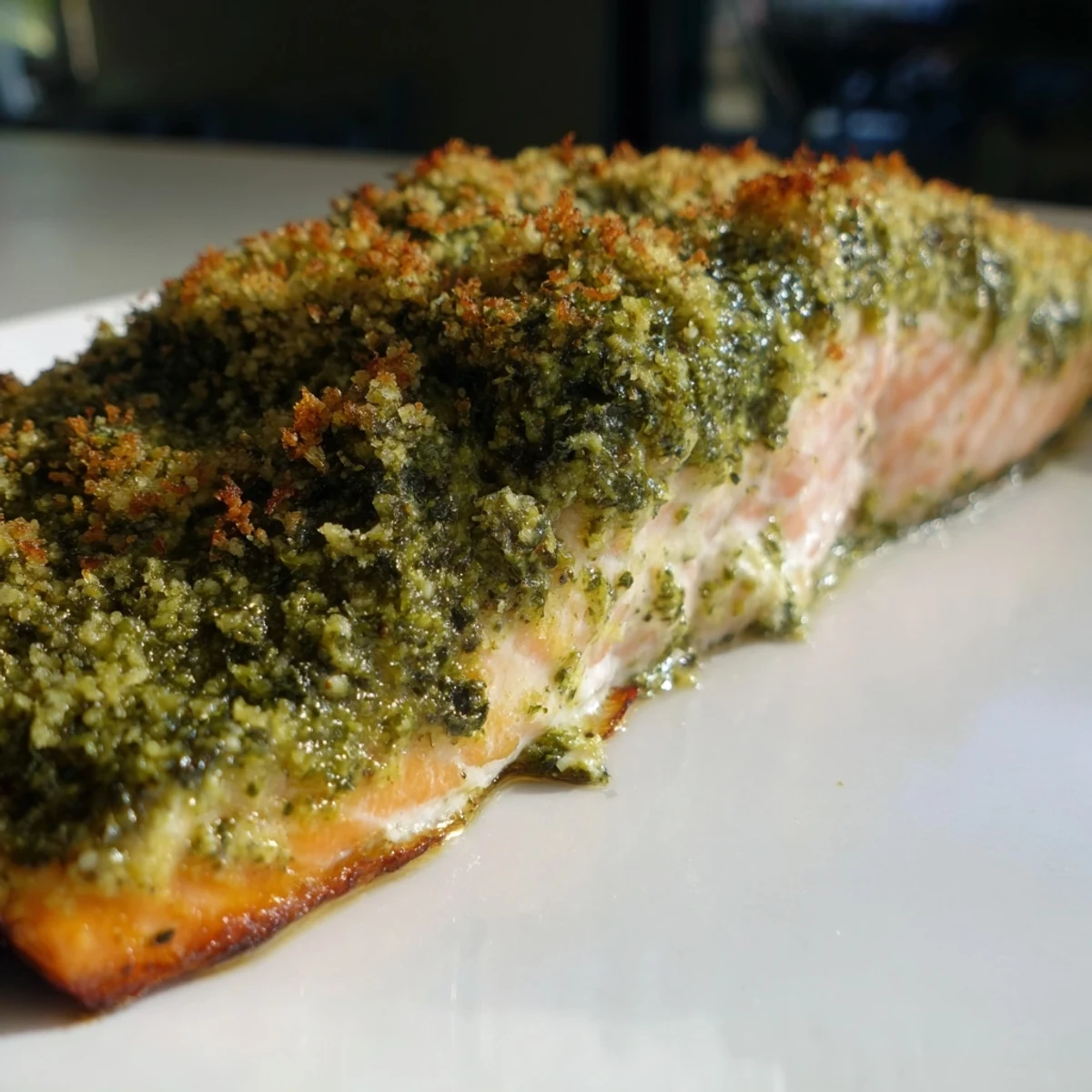 Tender oven-baked salmon topped with a crispy Parmesan and pesto crust, served alongside a glass of chilled white wine for a Mediterranean dinner.