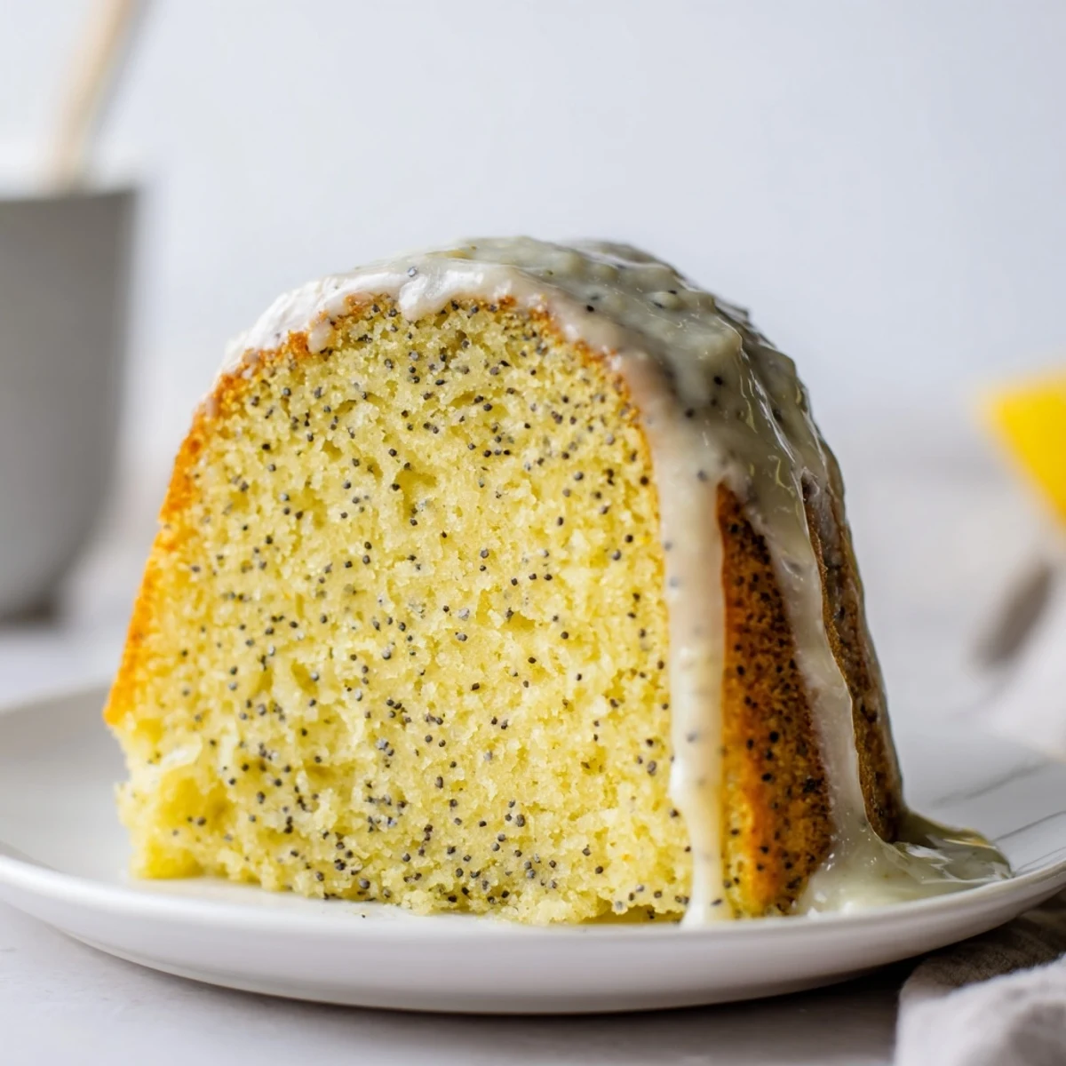 Slices of moist Lemon Poppy Seed Bundt Cake are plated with a dollop of whipped cream.