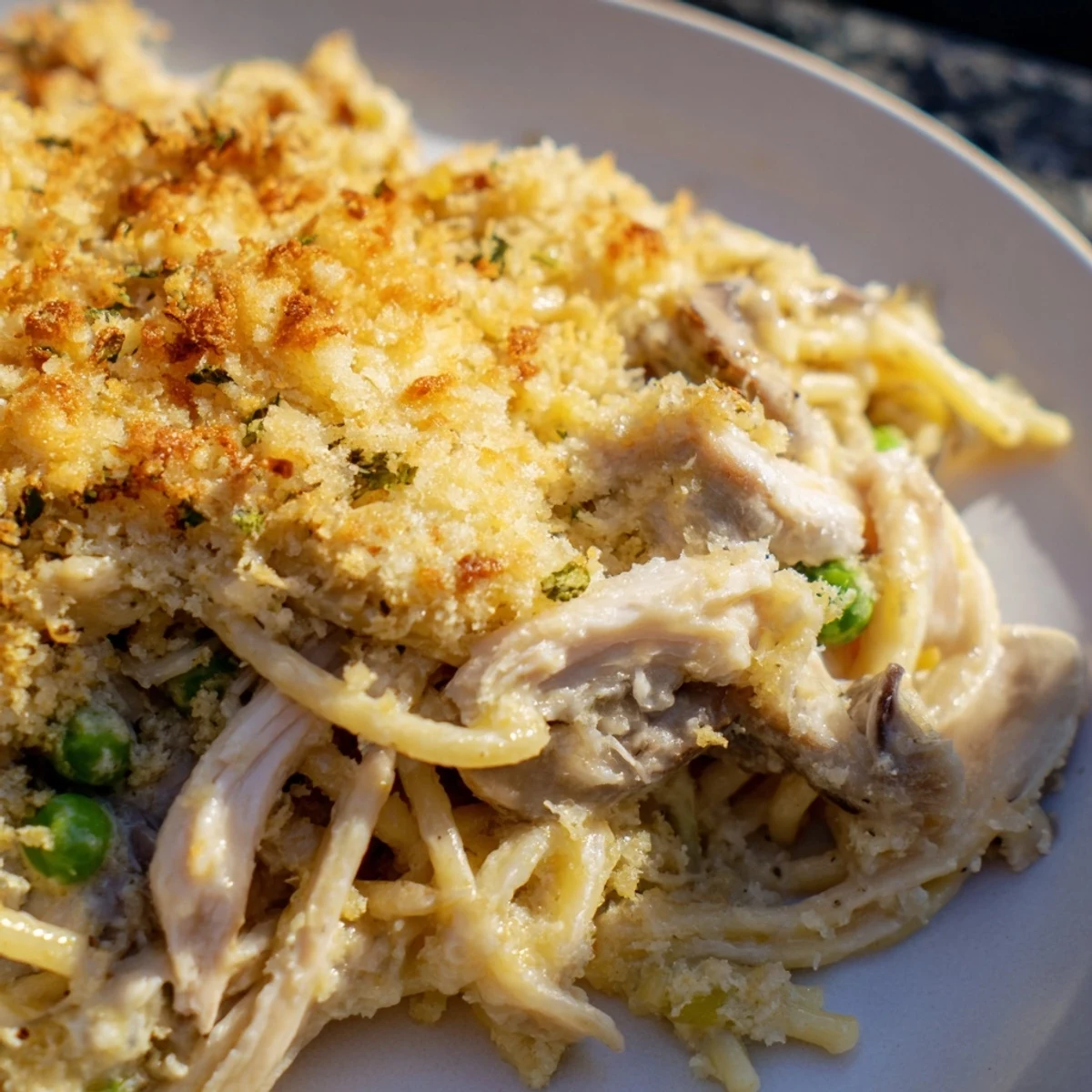 Golden-brown Turkey Tetrazzini with mushrooms and turkey in a creamy sauce, served in a white baking dish.