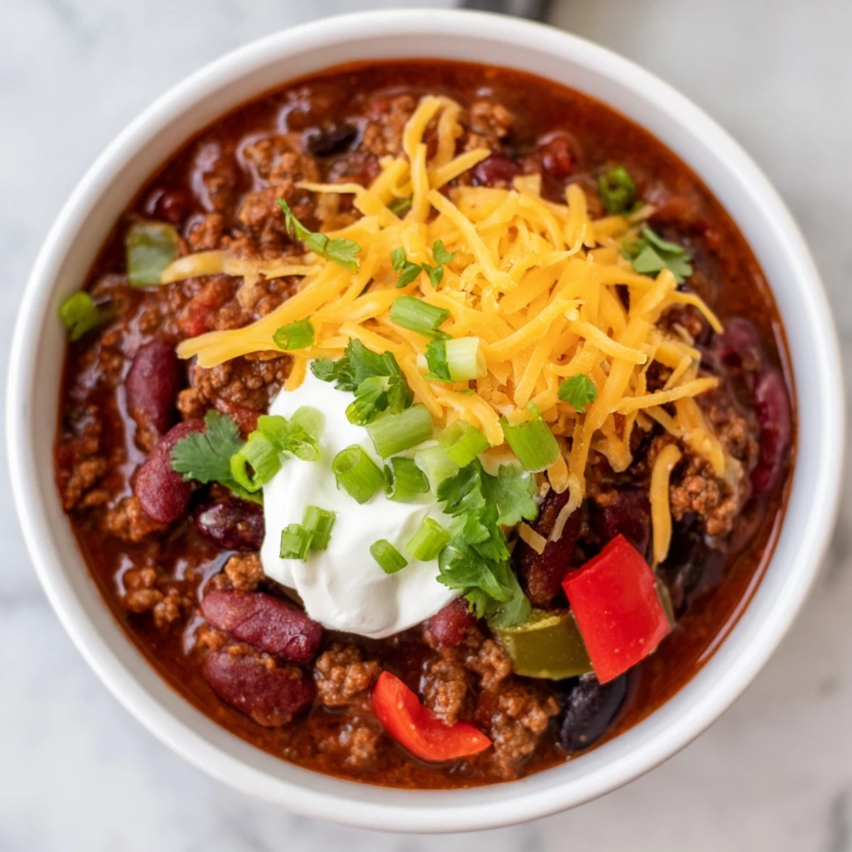 Slow Cooker Chili with Ground Beef in a rustic pot, surrounded by fresh ingredients like diced peppers, onions, and beans.