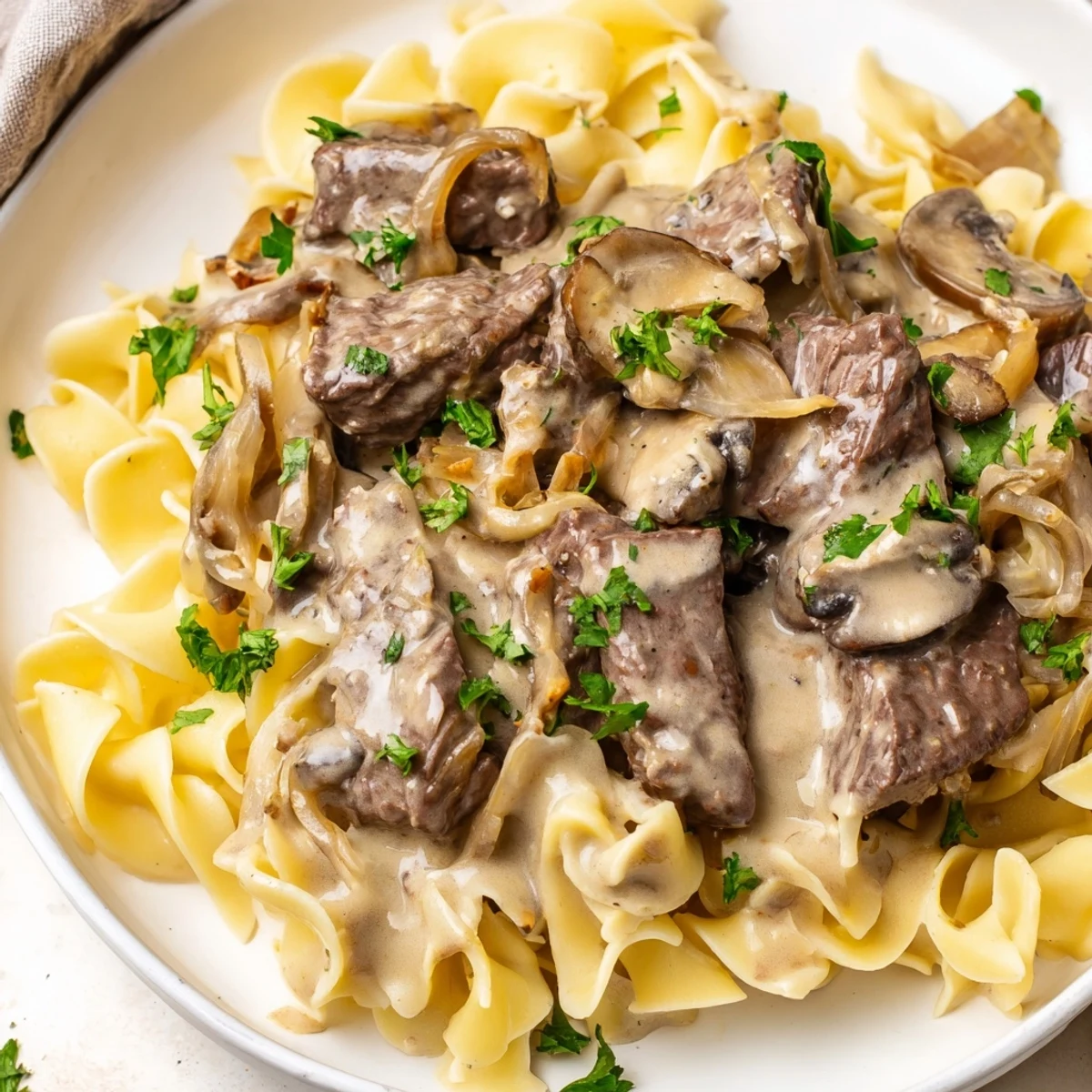 Savory beef strips and sautéed mushrooms in a rich sauce, piled high over buttery egg noodles for a comforting dinner.