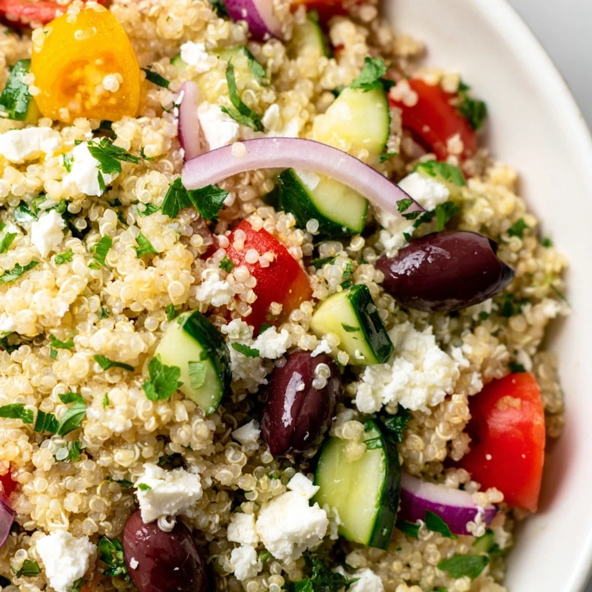 Fluffy quinoa Mediterranean salad with cucumbers, tomatoes, olives, and feta tossed in lemon-herb dressing.