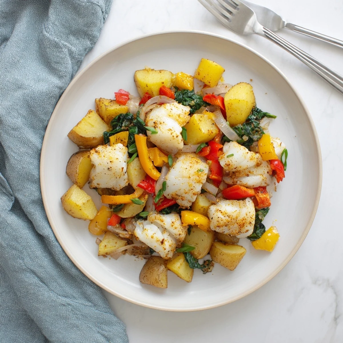 Hearty baked fish breakfast hash with sautéed veggies and crispy potatoes in a skillet.  