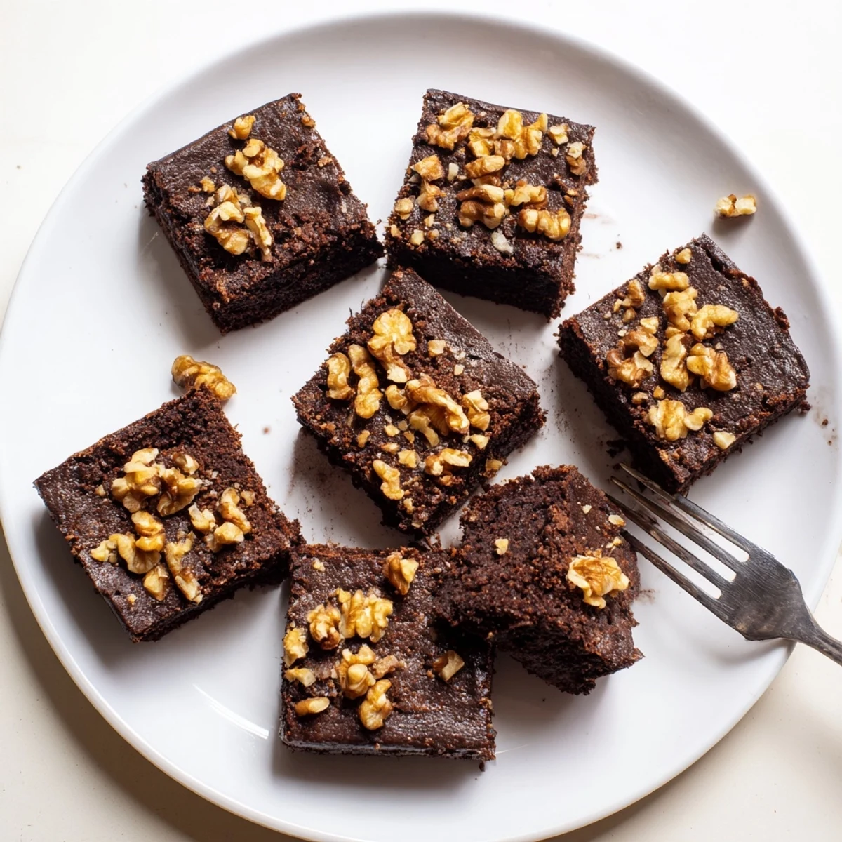 Freshly baked Chocolate Fudge Brownies with Walnuts sit on a wire rack, showing a moist, crackly top and fudgy interior studded with crunchy nuts.