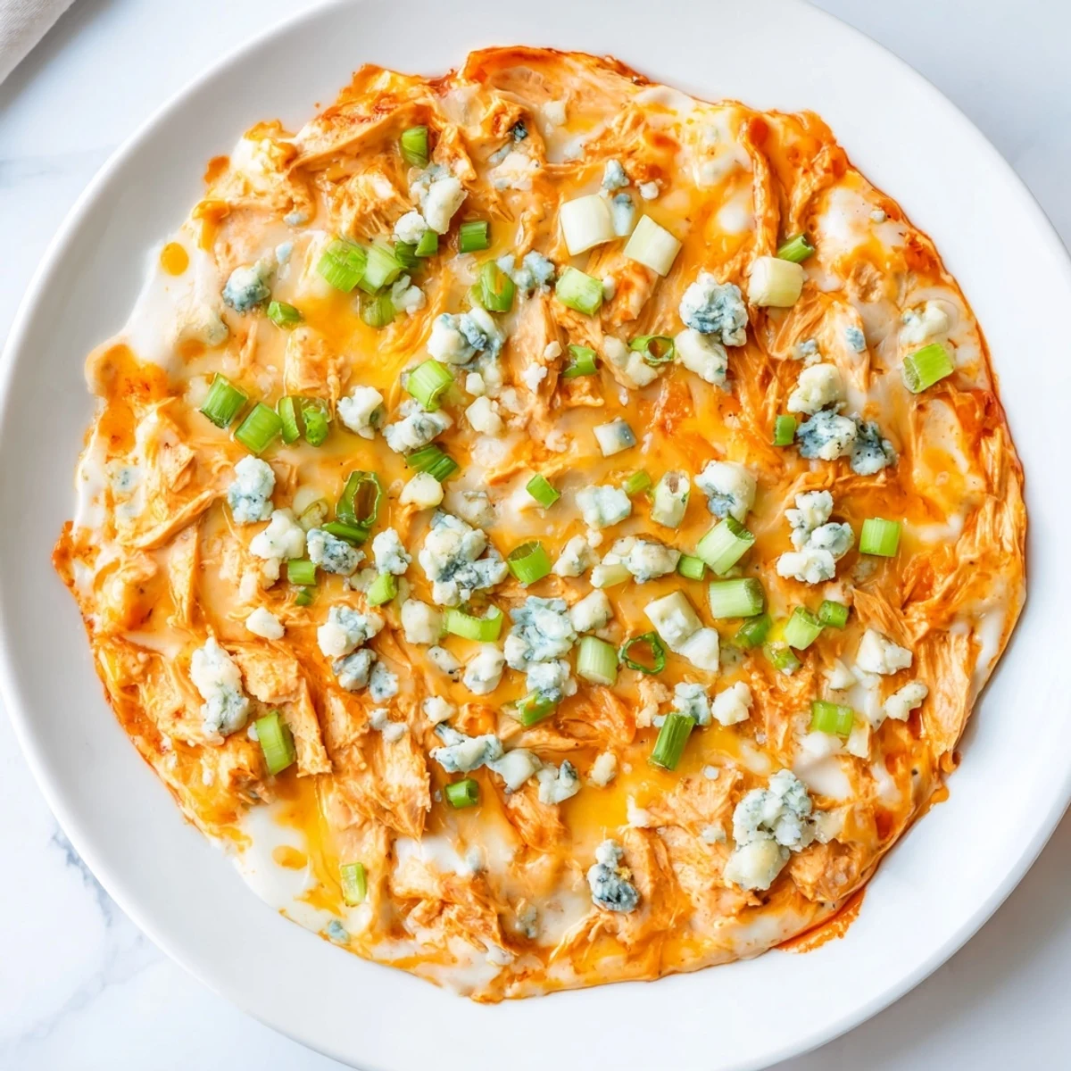 Freshly baked Keto Buffalo Chicken Dip, with bubbly cheese and shredded chicken, served warm alongside celery sticks.