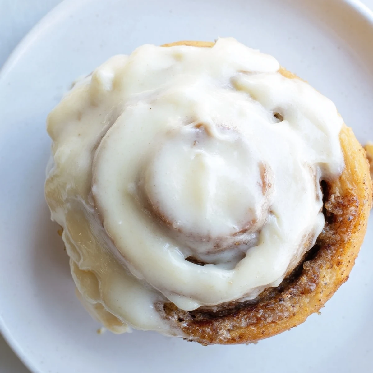 A single Keto Cinnamon Bun on a wooden board shows the tender, low-carb interior and sweet icing.