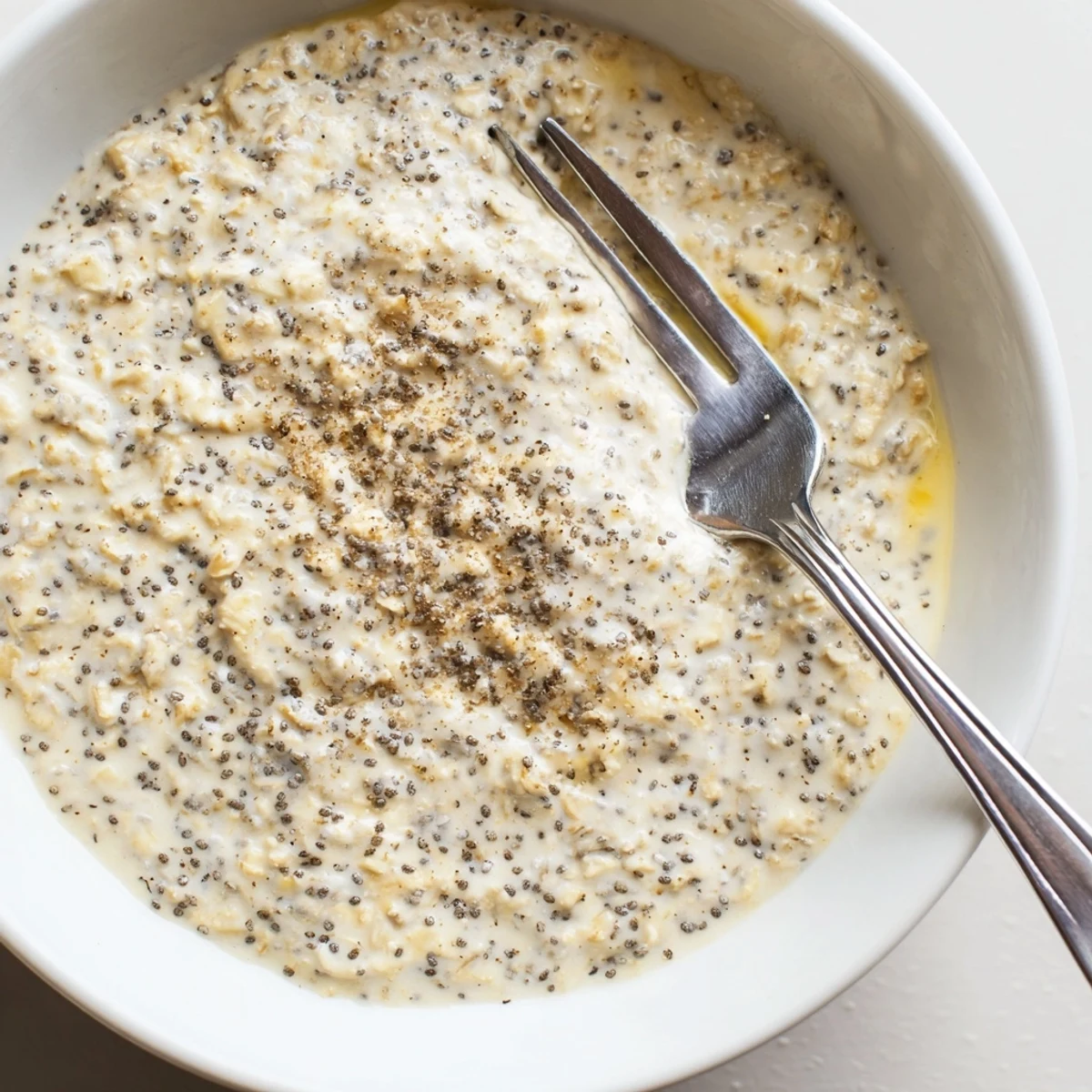 A close-up of vegan lemon poppy seed overnight oats in a glass jar, showing creamy texture and visible poppy seeds.