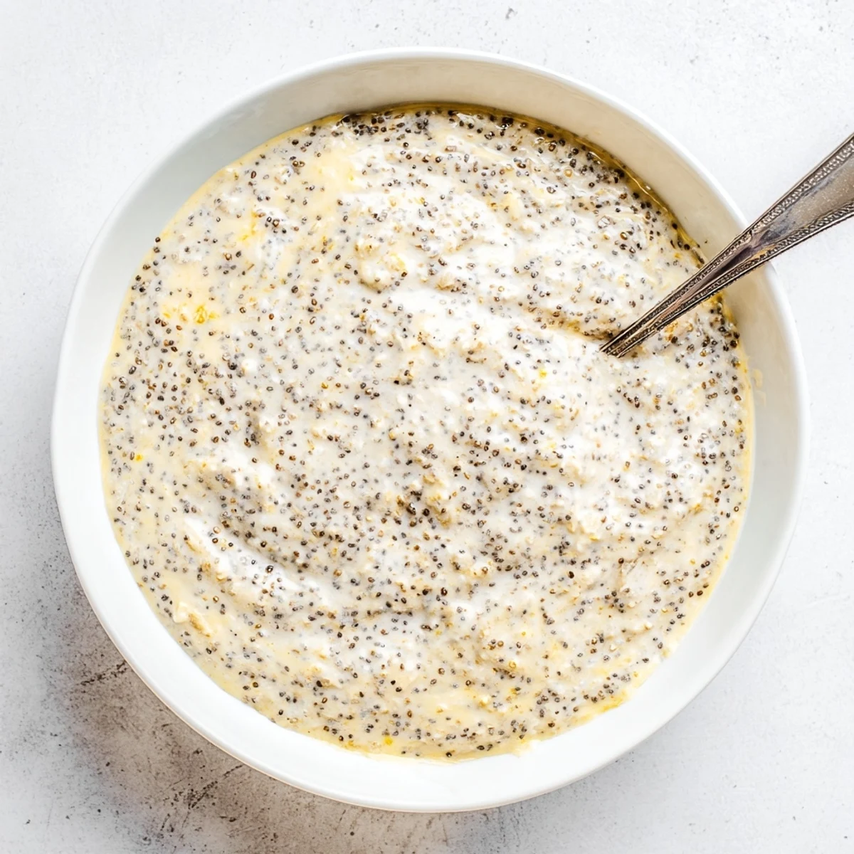 Spoon-ready vegan lemon poppy seed overnight oats topped with fresh blueberries and sliced almonds for a tangy, nutritious start.