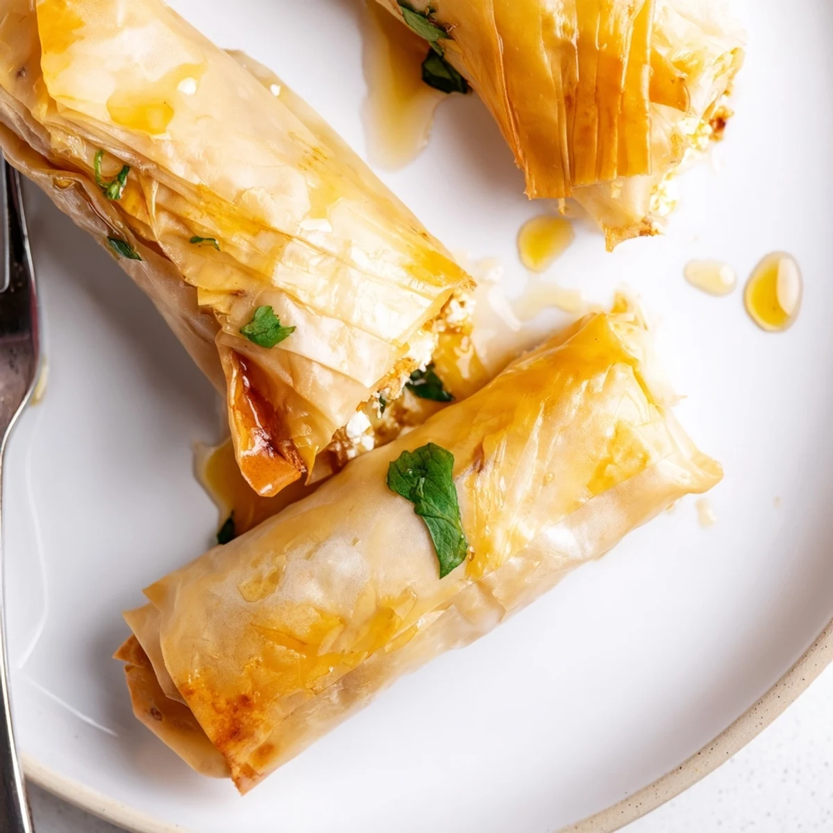 A close view of Oven Fried Feta Rolls With Chili Honey, showing flaky pastry and a sweet spicy drizzle.