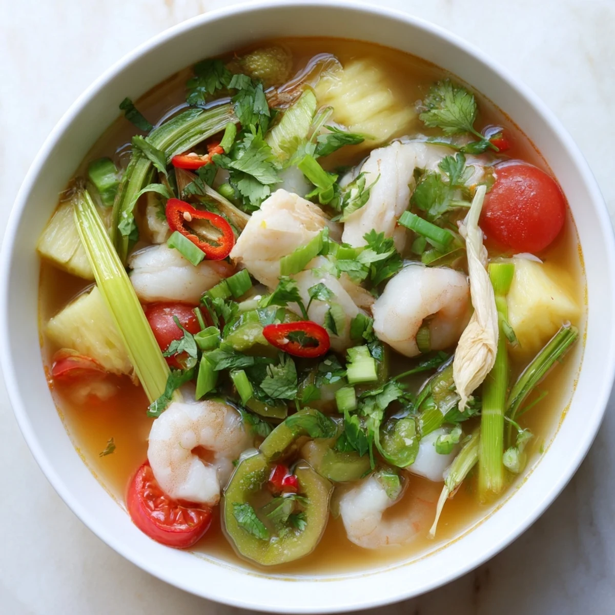 A close-up of Canh Chua shows fresh bean sprouts and aromatic herbs topping the sweet and sour fish broth in a rustic bowl.