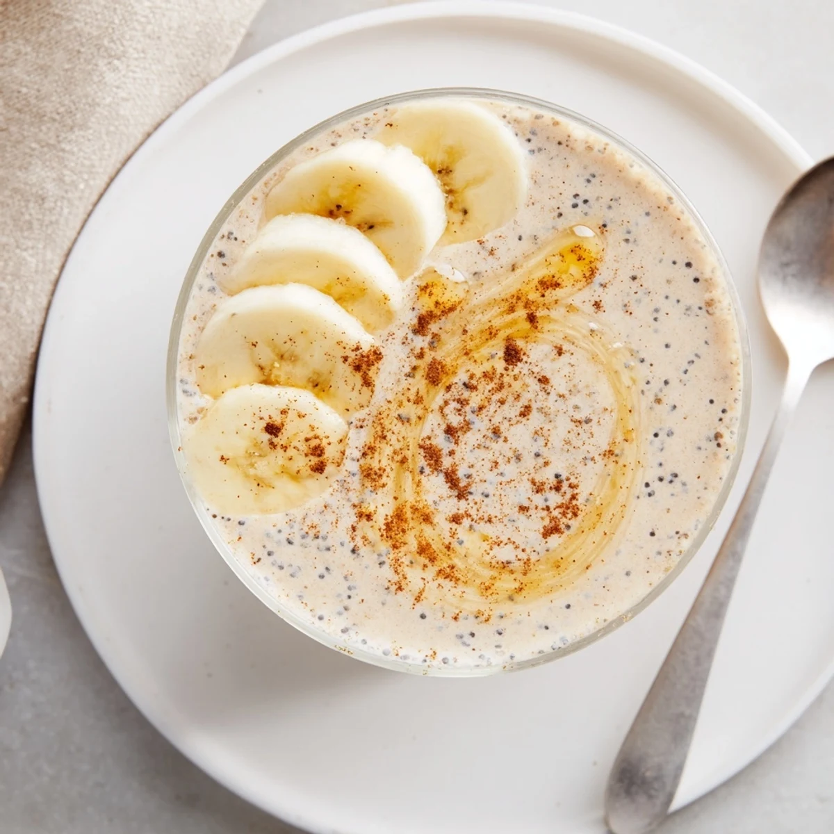 Creamy Greek yogurt banana smoothie poured into a glass topped with fresh banana slices