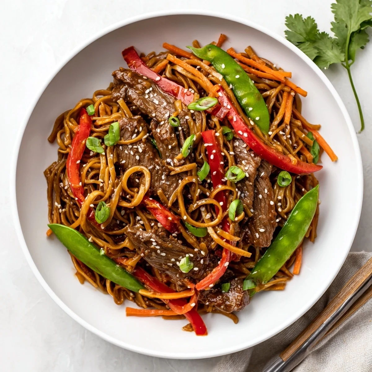 Glossy sticky beef noodles tossed with tender sliced steak and colorful crisp vegetables in a rich sweet-savory sauce