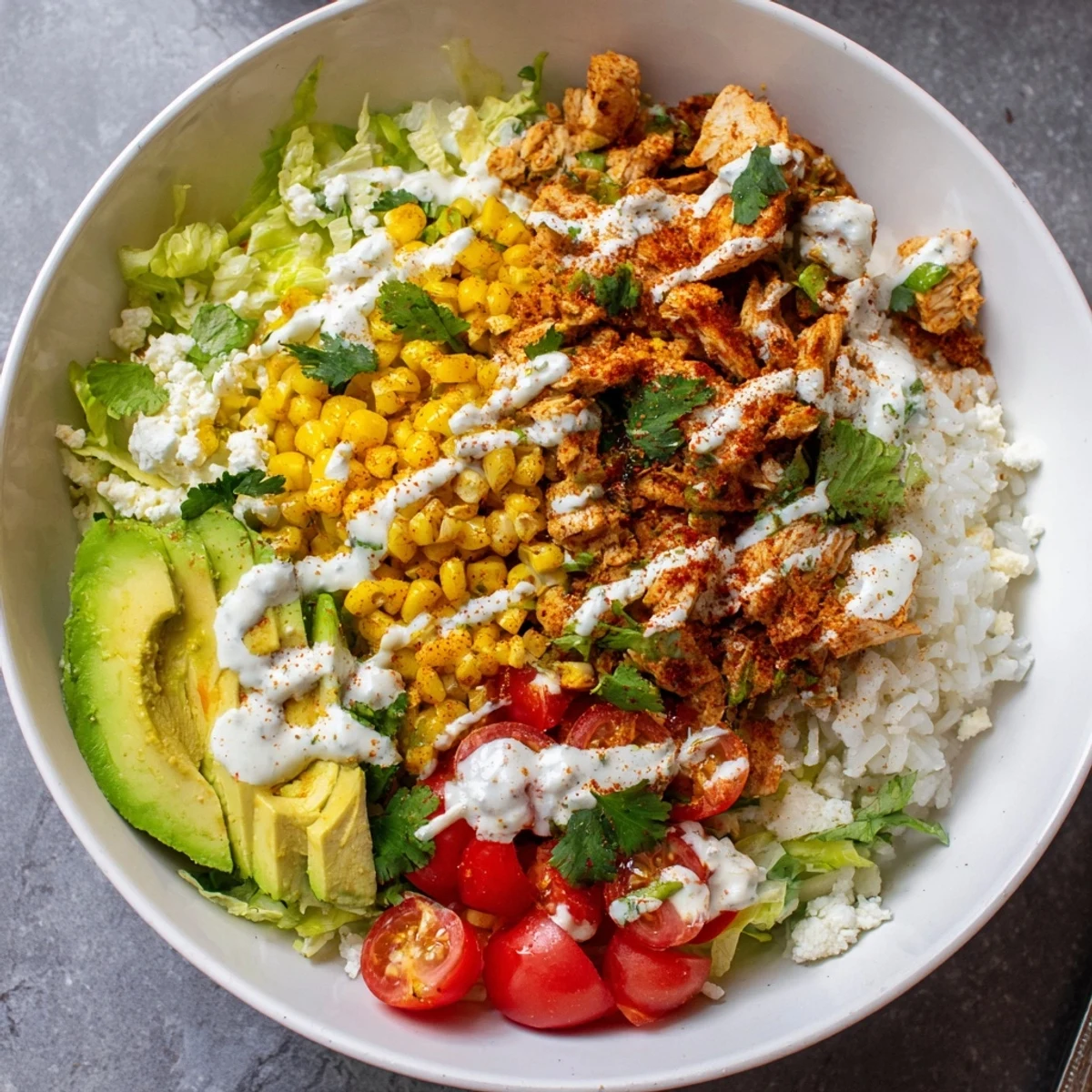 Vibrant street corn chicken bowl featuring juicy grilled chicken, roasted corn kernels, creamy cotija cheese, and zesty lime crema drizzled over fluffy rice and crisp romaine lettuce.