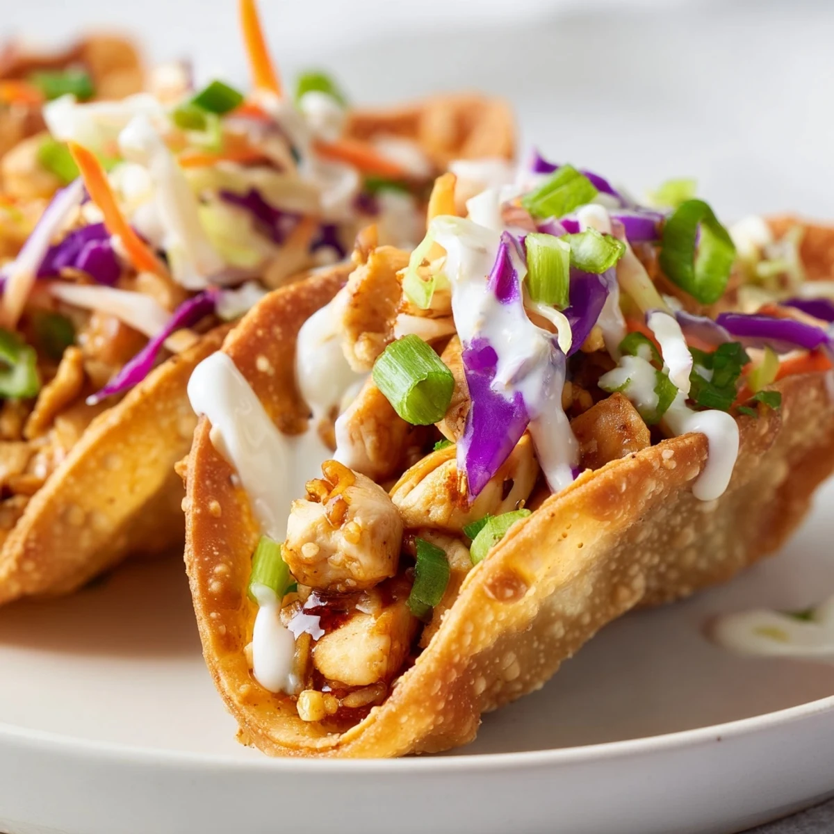 Baked golden wonton tacos bursting with tender chicken pieces topped with vibrant slaw and spicy mayo