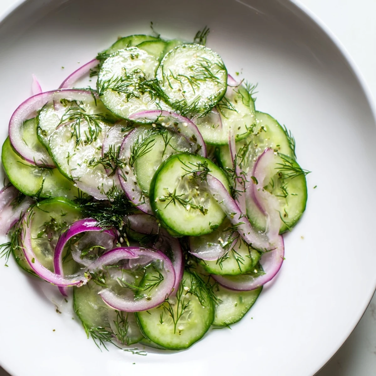 Crisp cucumber salad features thinly sliced vegetables coated in a light oil and vinegar dressing for summer picnics