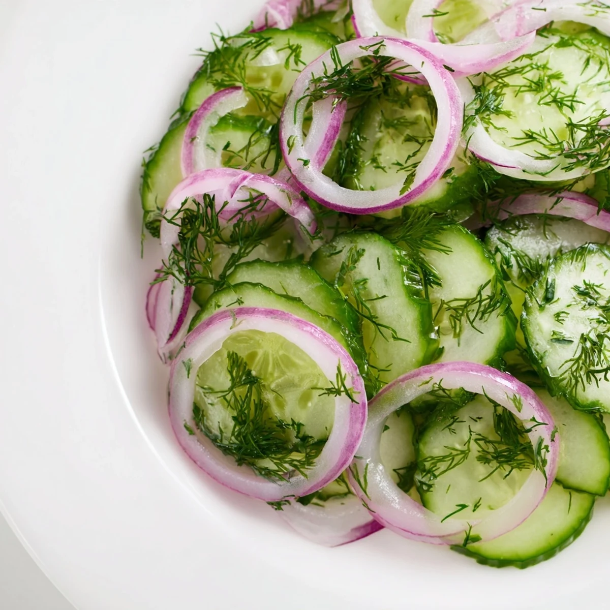 Easy refreshing cucumber salad displays vibrant green cucumbers with purple red onion and fresh dill garnish