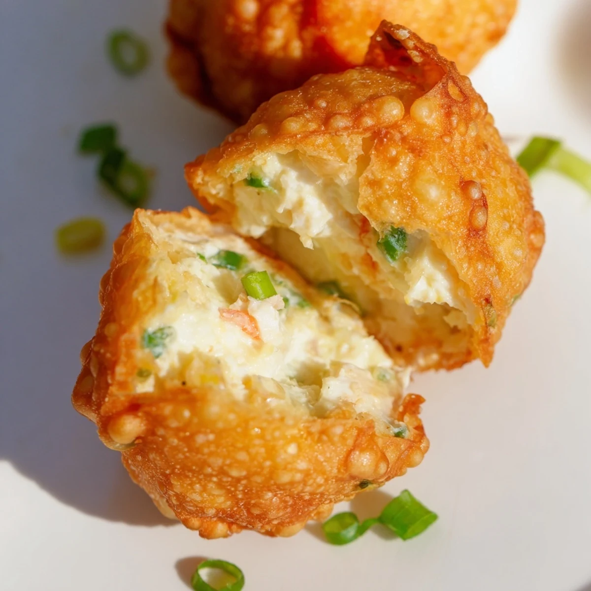 Golden brown crab Rangoon bombs with crispy fried wonton wrapper exterior and creamy crab cheese filling