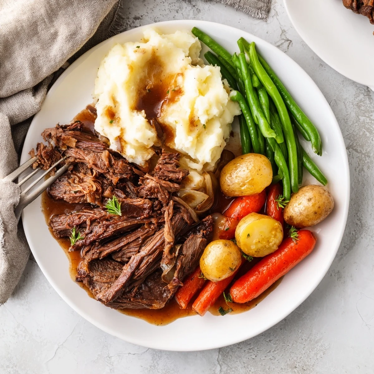 Comforting Southern style pot roast plated with fluffy mashed potatoes and seasoned green beans for a hearty dinner