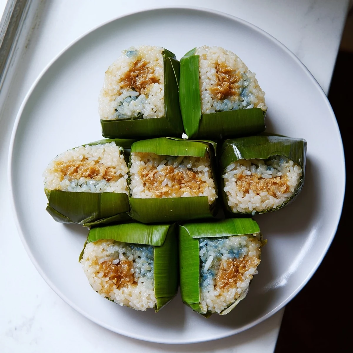 Traditional Malaysian Pulut Inti wrapped in banana leaves with fragrant coconut topping