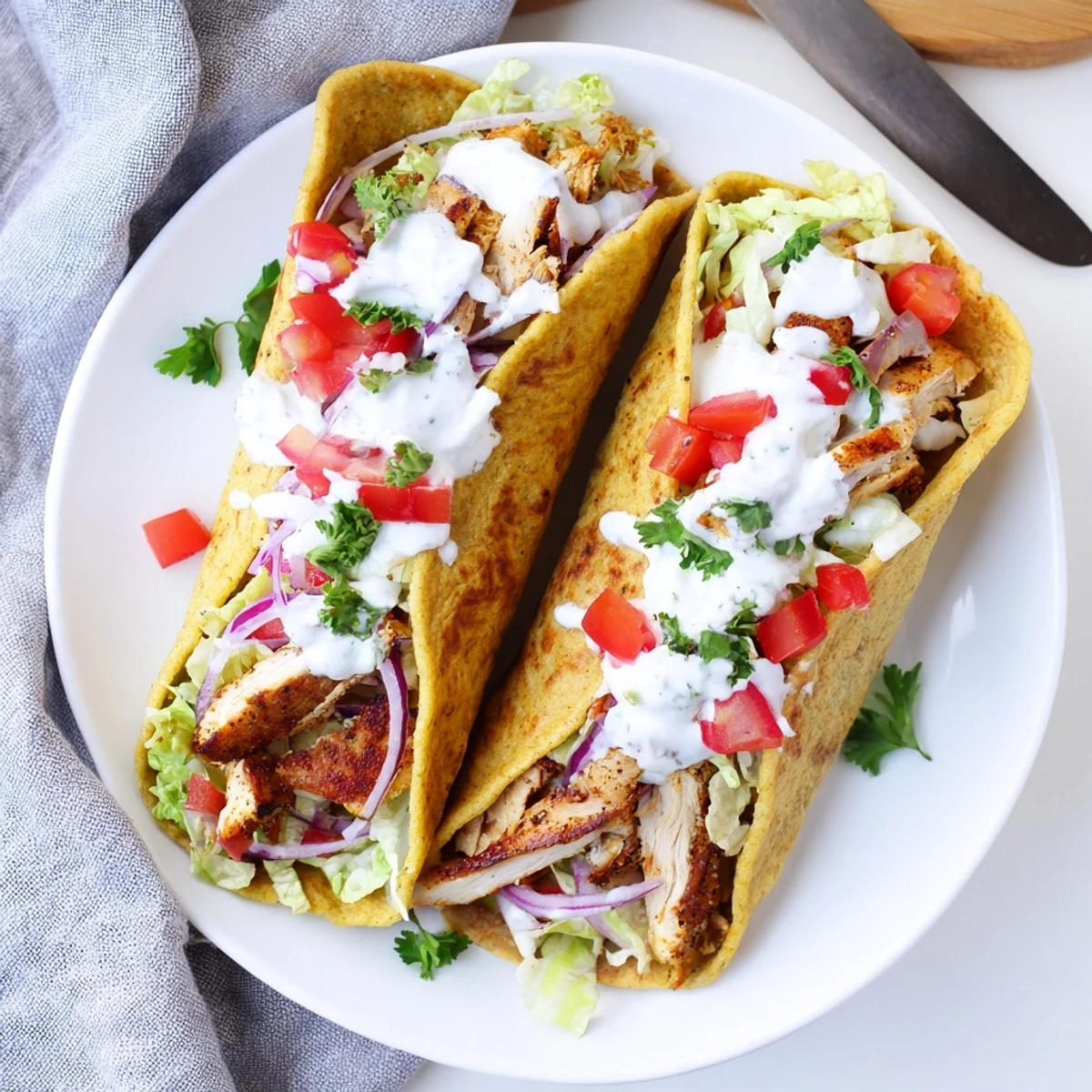 Protein-packed cottage cheese flatbread chicken wraps topped with lettuce, tomato, and creamy yogurt sauce