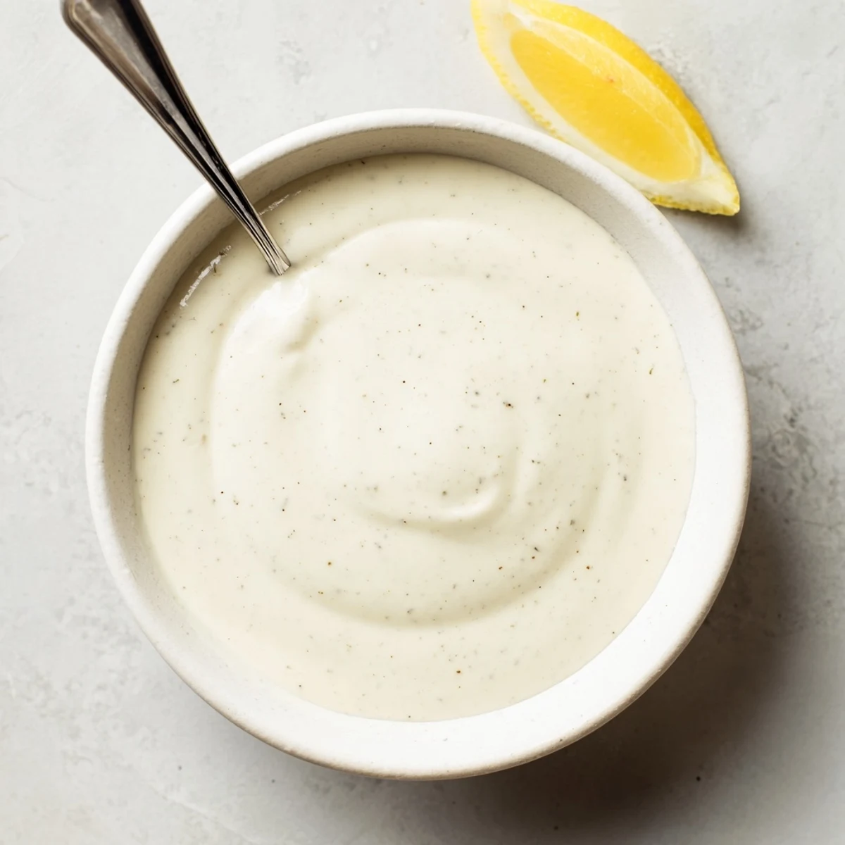 Thick white sauce with visible herbs speckled throughout, perfect spooned atop chicken shawarma wraps and salads