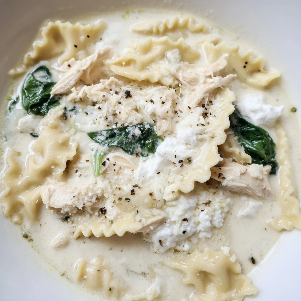 Creamy white lasagna soup loaded with tender chicken, wilted spinach, and melted mozzarella in a steaming bowl