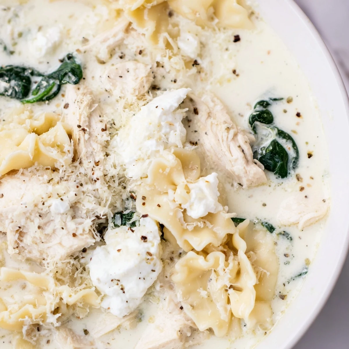 Rich and creamy white lasagna soup with broken noodles, shredded chicken, and a golden cheesy broth