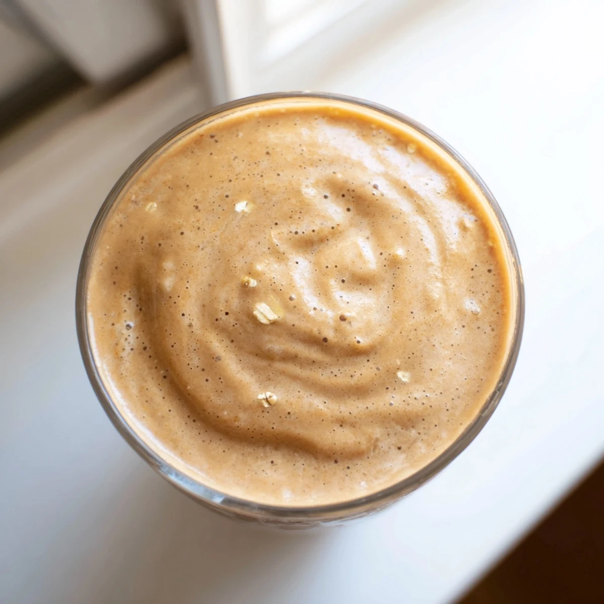 Creamy coffee smoothie in a glass topped with a sprinkle of cinnamon