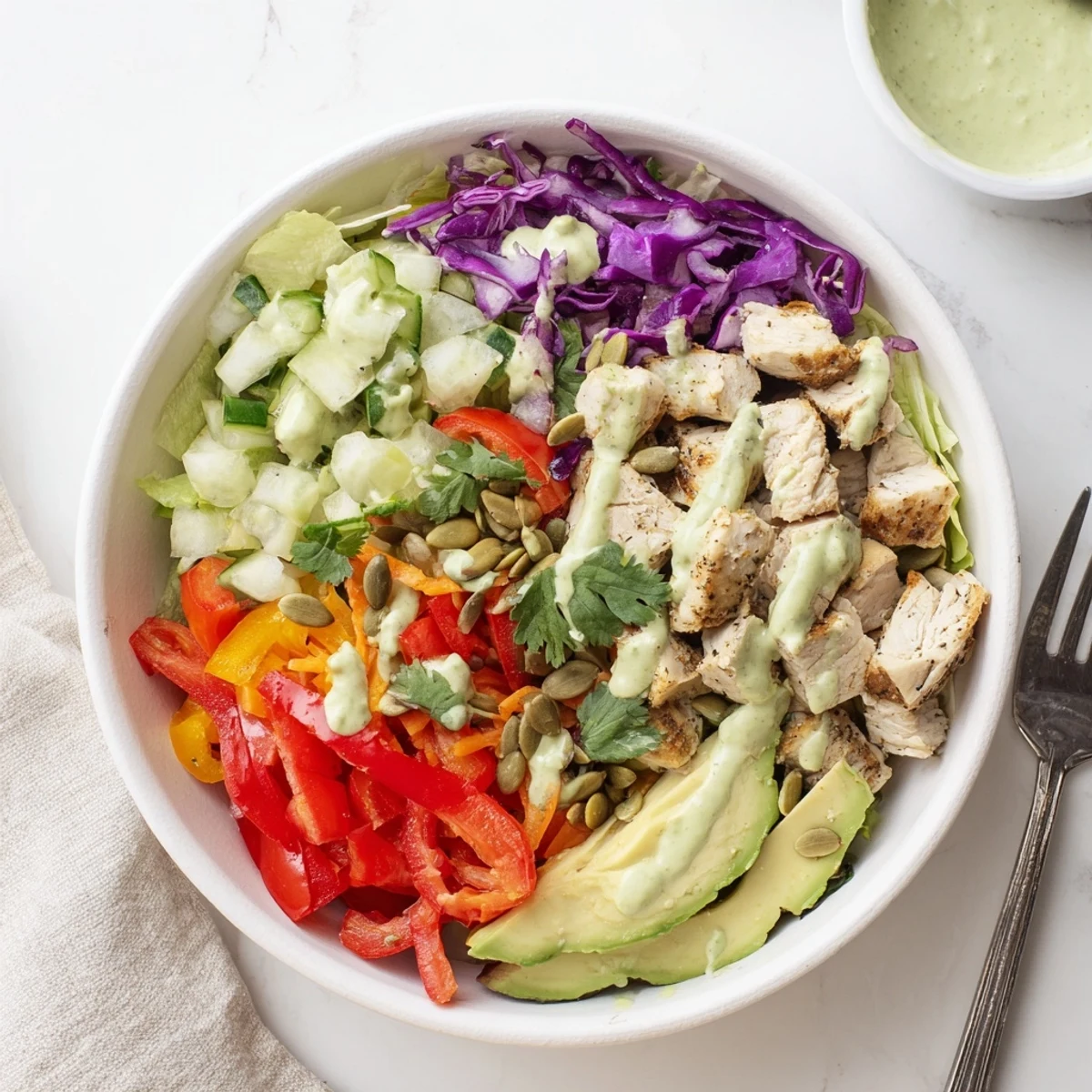 Colorful keto bowls with seasoned chicken, crisp vegetables, and creamy avocado dressing ready to serve