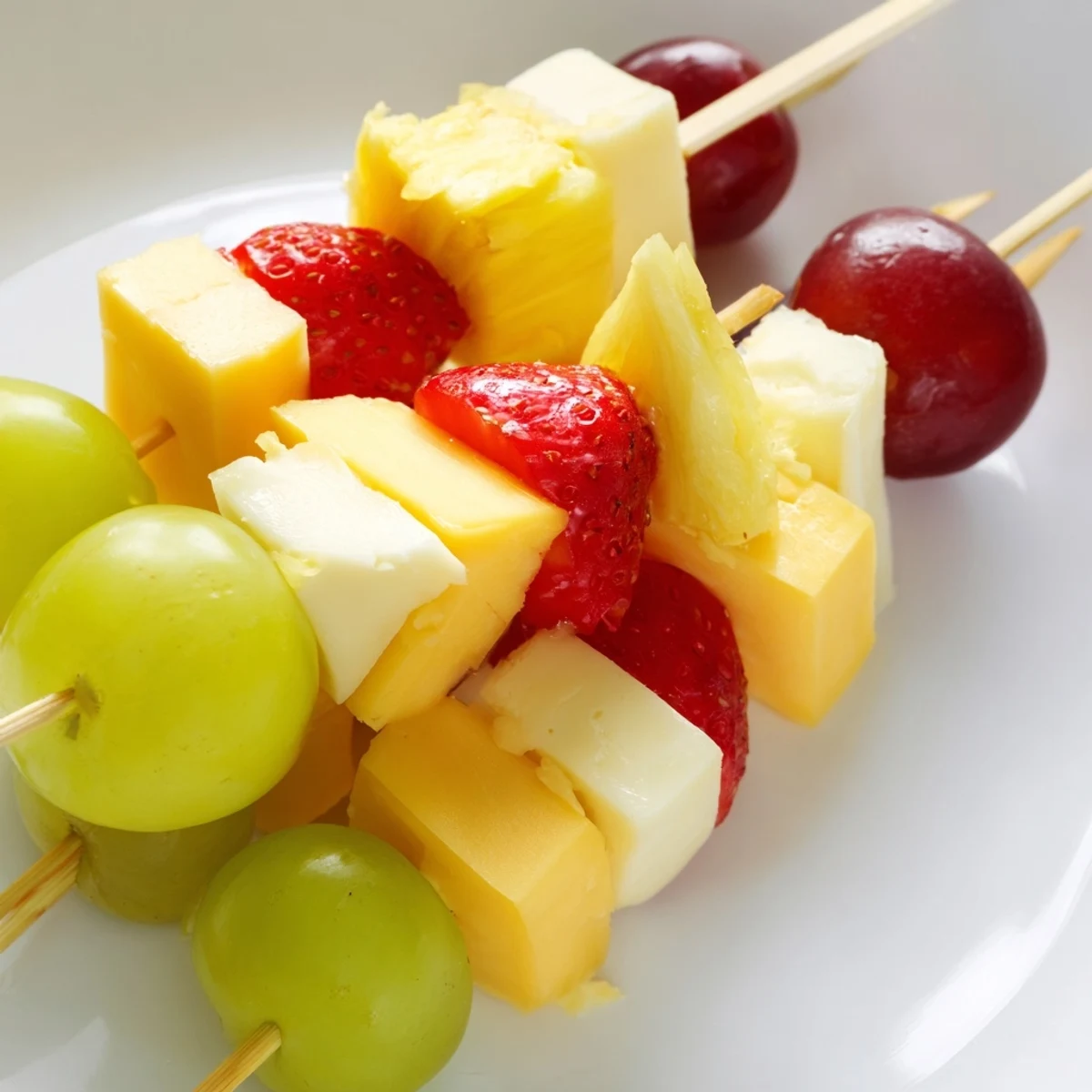 Colorful fruit and cheese kabobs featuring ripe grapes pineapple and creamy Monterey Jack skewers