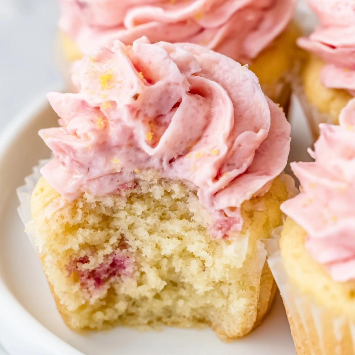 Fresh strawberry lemonade cupcakes topped with creamy pink frosting and bright lemon zest