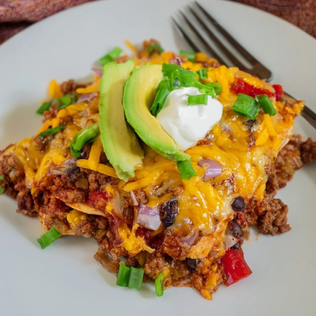 Layered corn tortillas and black beans in hot Beef Skillet Enchiladas with cheddar.