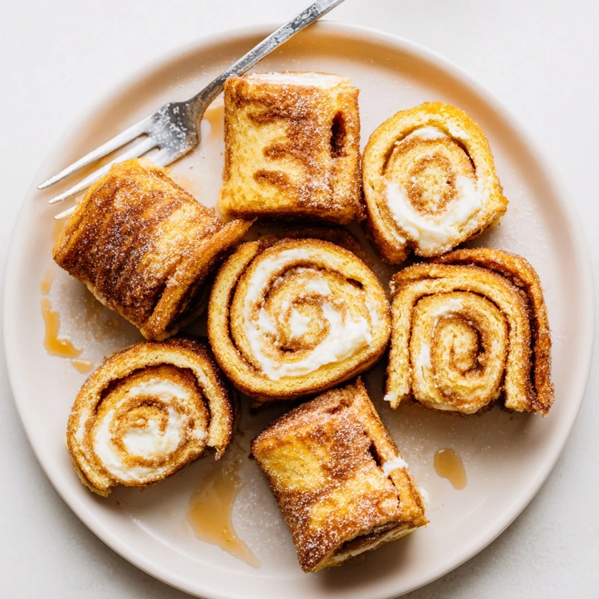 Skillet-browned Cinnamon Roll French Toast Roll Ups served with warm maple syrup