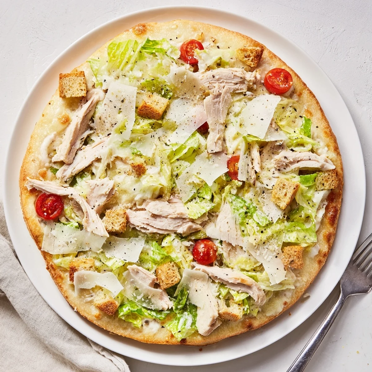 Sliced Chicken Caesar Salad Pizza Recipe topped with bubbling mozzarella, juicy chicken, crunchy croutons
