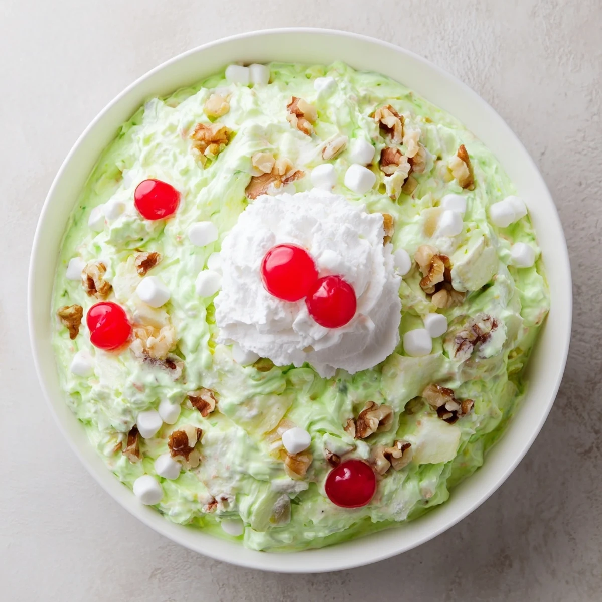 Retro Watergate Salad recipe showing the pistachio pineapple dessert flecked with chopped walnuts and mini marshmallows