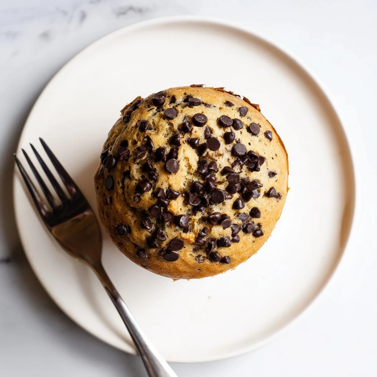 Moist homemade banana chocolate chip muffins bursting with semi-sweet chocolate chips in a paper liner