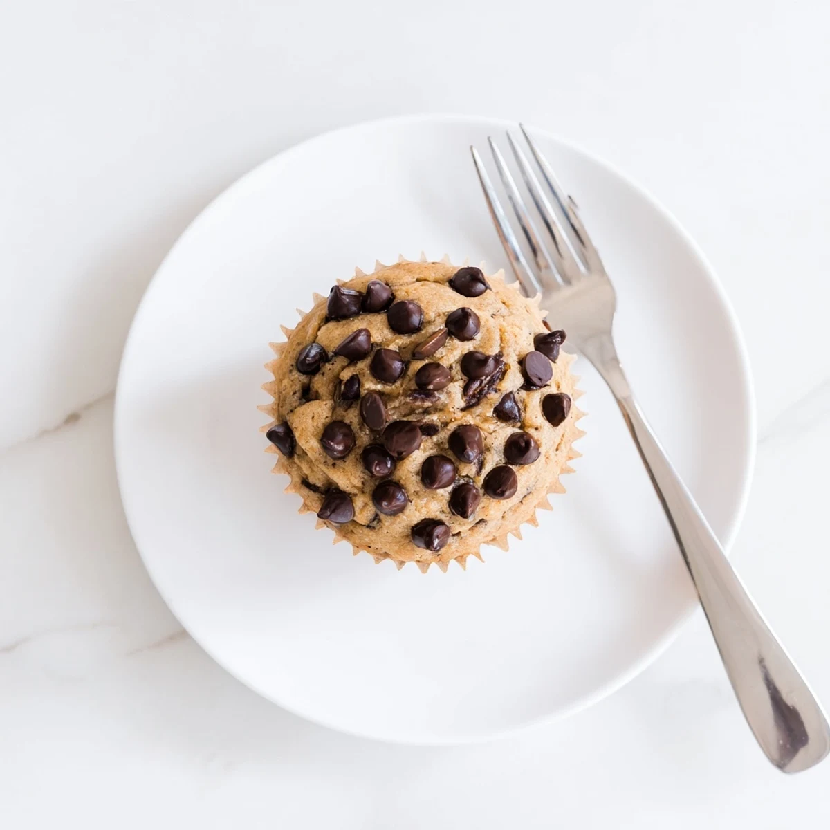 Stack of fluffy banana chocolate chip muffins with ripened banana mash and chocolate throughout