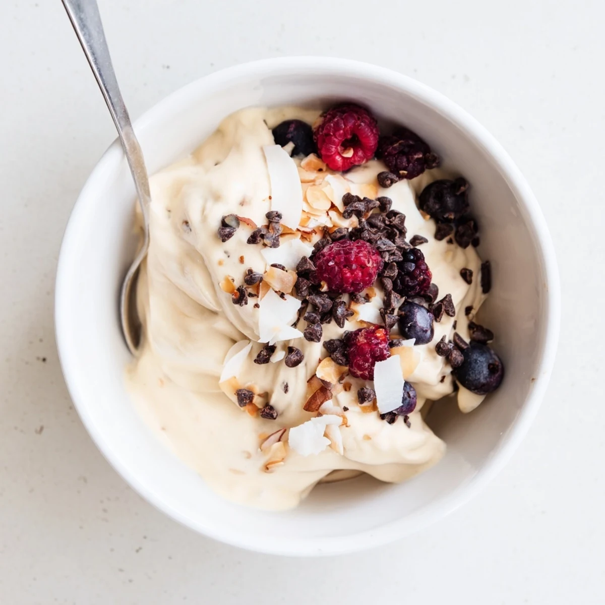 Creamy healthy nice cream recipe topped with fresh berries and coconut flakes in a bowl