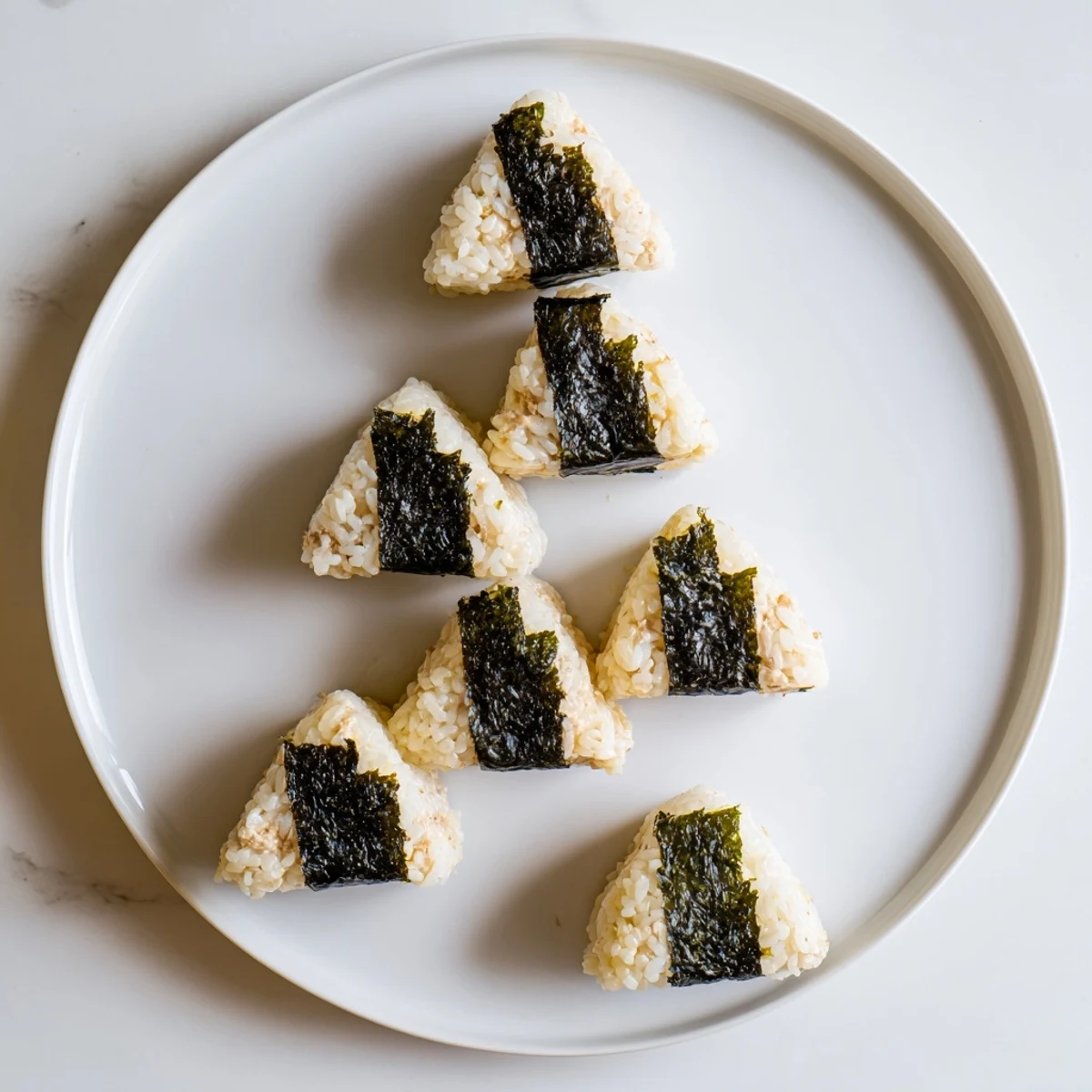 Freshly shaped Japanese onigiri stuffed with creamy tuna mayonnaise filling centered in white rice