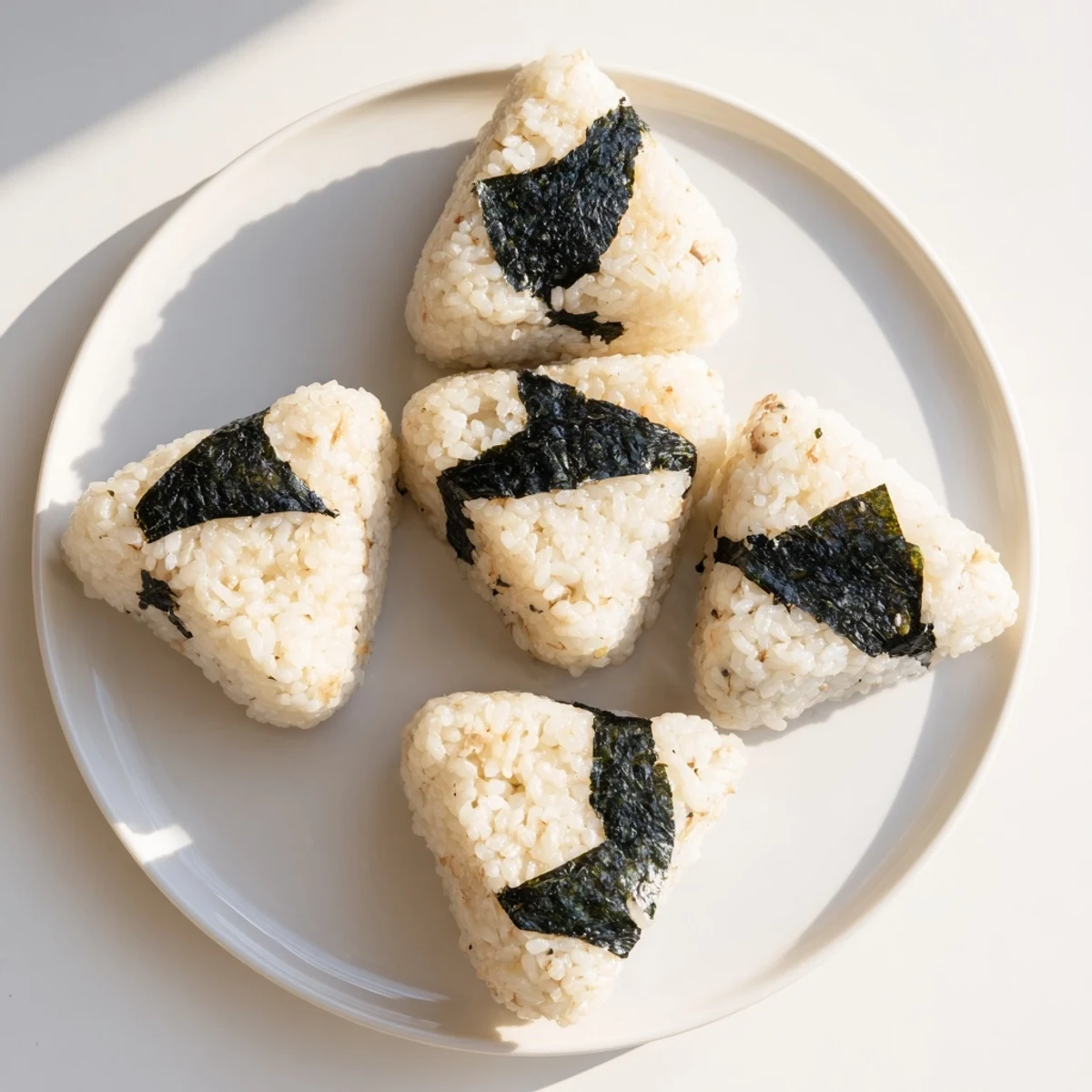 Close-up of triangle tuna mayo onigiri garnished with dark nori for easy handheld snacking